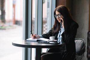 jovem empresária falando em a telefone dentro café fazer compras foto