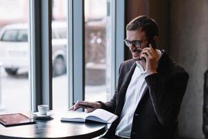 bonito homem de negocios falando em a telefone dentro uma cafeteria. foto