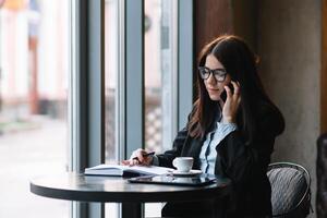 jovem empresária falando em a telefone dentro café fazer compras. foto