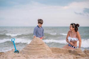 mãe e filho jogando em a de praia às a pôr do sol tempo. conceito do amigáveis família foto