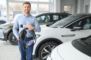 conceito do comprando elétrico veículo. bonito o negócio homem carrinhos perto elétrico carro às concessionária foto