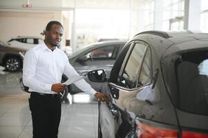 carros concessionária conceito. auto vendedor afro homem em pé dentro automóvel Centro foto