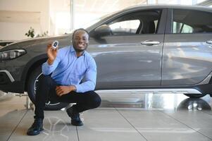 dele Sonhe carro. feliz jovem africano homem olhando animado escolhendo uma carro às a concessionária foto