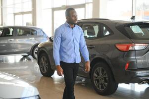bonito africano homem escolhendo uma Novo carro às a concessionária foto
