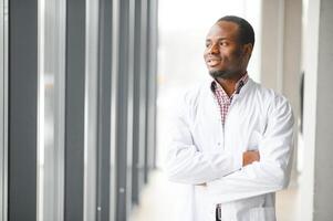 retrato do jovem masculino doutor, em pé contra janela às hospital corredor foto