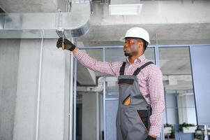 hvac africano trabalhador instalar canalizado tubo sistema para ventilação e ar condicionamento. cópia de espaço foto