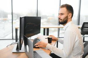 criptografia comerciante senta às dele local de trabalho dentro frente do uma monitor com gráficos. foto