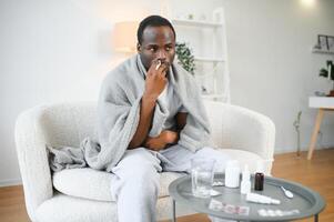 frio e gripe tratamento. doente africano americano homem usando nasal spray foto