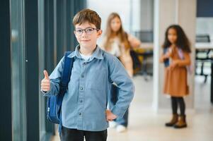 estudante com o saco da escola e livros dentro a escola. Educação conceito. costas para escola. aluno indo para aula. à moda Garoto com mochila. Garoto pronto para estude foto