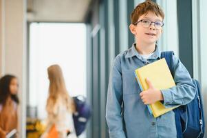 estudante com o saco da escola e livros dentro a escola. Educação conceito. costas para escola. aluno indo para aula. à moda Garoto com mochila. Garoto pronto para estude foto