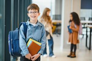 estudante com o saco da escola e livros dentro a escola. costas para escola foto