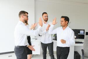 feliz pessoas de negócio rindo enquanto colaborando em uma Novo projeto dentro a escritório. grupo do diverso pessoas de negócio trabalhando juntos dentro uma moderno área de trabalho foto