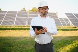 Senior engenheiro trabalhando em solar painel Fazenda. a conceito do verde energia foto