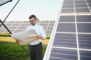 solar poder plantar. homem em pé perto solar painéis. renovável energia foto