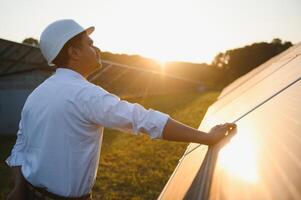 retrato do uma jovem indiano masculino engenheiro ou arquiteto às uma solar painel Fazenda. a conceito do limpar \ limpo energia foto