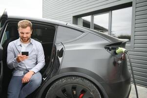 uma homem cobranças a elétrico carro foto