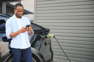 africano americano homem cobrando dele elétrico carro. foto