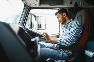 indiano caminhão motorista verificação envio Lista enquanto em pé em estacionamento muitos do distribuição armazém. foto