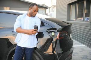 africano americano homem cobrando dele elétrico carro. foto