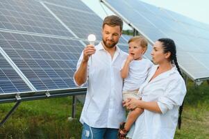 a conceito do renovável energia. jovem feliz família perto solar painéis foto