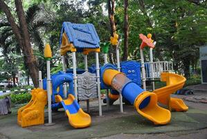 colorida crianças Parque infantil em a gramado dentro a parque. lindo cidade verde parque com árvores foto