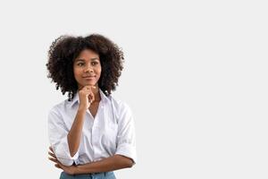 retrato do africano americano mulher pensando sobre alguma coisa interessante ou pensando alguma coisa acima. segurando dela queixo enquanto em pé em branco fundo. foto