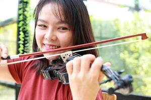 ásia mulher jogando clássico instrumento violino às casa dentro a manhã. ela goza jogando música. internacional música Educação conceito Aprendendo e praticando. banda e viver música foto