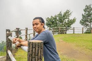 jovem homem ficar de pé em a Relva campo cavalo arena. a foto é adequado para usar para calma curtiu atividade, lazer atividade e parque fundo.