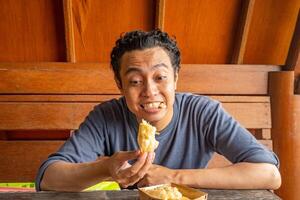 homem expressão feliz, sorriso, surpreso quando comer a banana fritas. a foto é adequado para usar para saudável Cuidado, homem expressão propaganda e diariamente atividade conteúdo meios de comunicação.