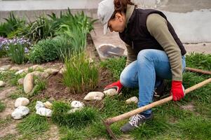 mulher deitado Fora decorativo pedras em uma canteiro de flores dentro a jardim, país vida conceito foto