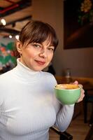 retrato do uma mulher com uma copo do café dentro uma cafeteria foto