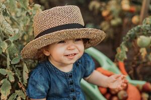 retrato do uma fofa pequeno menina dentro uma azul vestir e uma Palha chapéu dentro a outono jardim. jovem agricultor foto