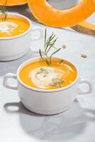 abóbora creme sopa com azedo creme, sementes e alecrim dentro uma prato em uma abóbora fundo foto