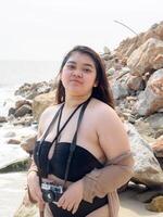 retrato jovem ásia mulher gordo gordo fofa lindo sorrir feliz Diversão apreciar relaxar bikini roupa de banho corpo sexy frente Visão mar de praia branco areia limpar \ limpo céu azul calma natureza oceano onda água viagem em feriado foto