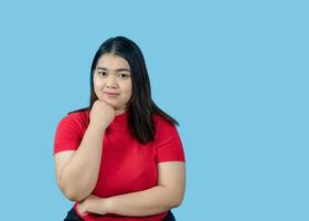 retrato menina jovem mulher ásia gordo gordo fofa lindo bonita 1 pessoa vestindo uma vermelho camisa é sentado sorridente apreciar alegremente olhando Uau para copyspace imaginário em a azul fundo foto