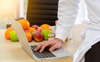 fechar-se do nutricionista mão usando computador portátil às trabalhar. cuidados de saúde e dietético consulta conceito. foto