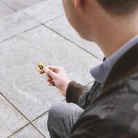 jovem homem segurando bitcoin moeda dentro dele mão foto
