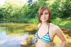 jovem mulher dentro bikini às lago foto