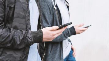 dois irreconhecível Móvel telefone viciado masculino adolescentes usando Smartphone foto