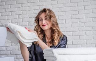 linda mulher segurando toalhas brancas limpas em casa foto