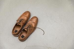 vintage masculino couro sapatos com atacadores em uma cinzento concreto fundo. foto