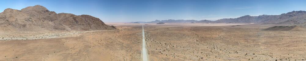 panorâmico zangão cenário do uma solitário cascalho estrada através a deserto foto