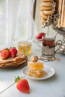 ainda vida dentro a russo tradição para maslenitsa, panquecas com querida e morangos, chá a partir de uma samovar com bagels foto