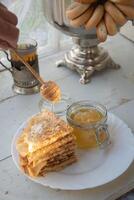 russo panquecas com querida e uma copo do chá a partir de uma vintage samovar maslenitsa festival conceito foto