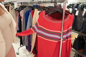 menina milenar dentro a loja escolhe em uma cabide Rosa blusa, moda roupas foto