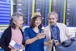 grupo do ásia família turista passageiro com Senior pai olhando às a saída mesa às aeroporto terminal para CIA aérea viagem e feriado período de férias foto