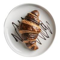 francês pastelaria uma chocolate coberto croissant senta em uma branco placa. a Boa padaria peça tem uma chocolate chuvisco em topo. foto