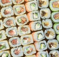 close-up de muitos rolos de sushi com recheios diferentes. tiro macro de comida japonesa clássica cozida. imagem de fundo foto