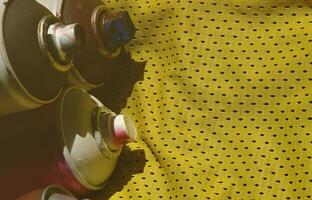 vários pulverizadores de tinta aerossol usados estão na camisa esportiva de um jogador de basquete feita de tecido de poliéster. o conceito de arte de rua juvenil, esportes ativos e estilo de vida agitado foto