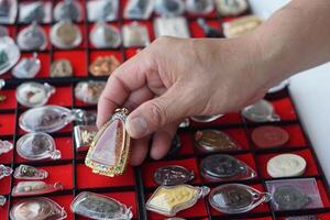 closeup mão segura amuleto de buda tailandês da coleção de amuletos. conceito, fé e crença para budista para santo e sorte. coleta de amuleto como passatempo, troca, venda ou compra foto